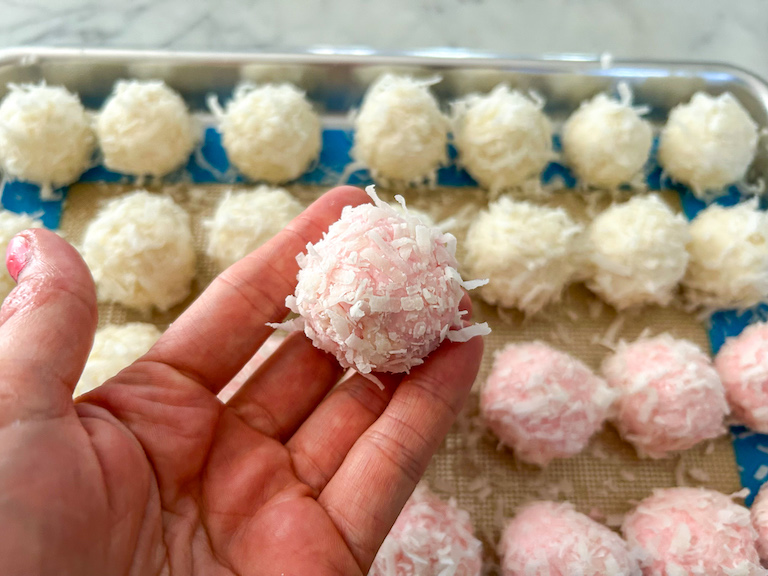 Hand holding a pink coconut truffle