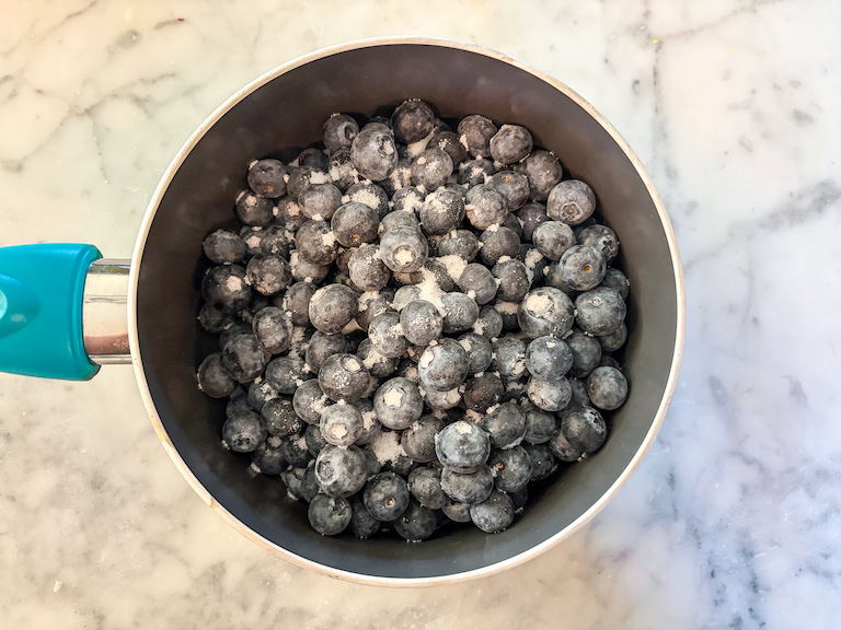 Blueberries and sugar in a saucepan