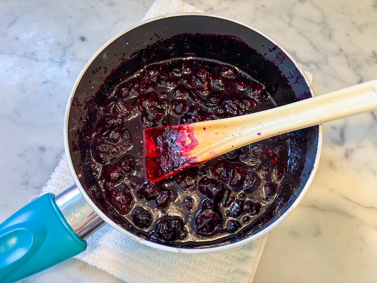 A pan of blueberry compote with a spoon