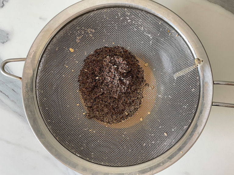 Passing tea-infused cream through a mesh strainer