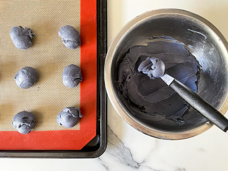 A melon baller scooping Earl Grey white chocolate ganache into truffles