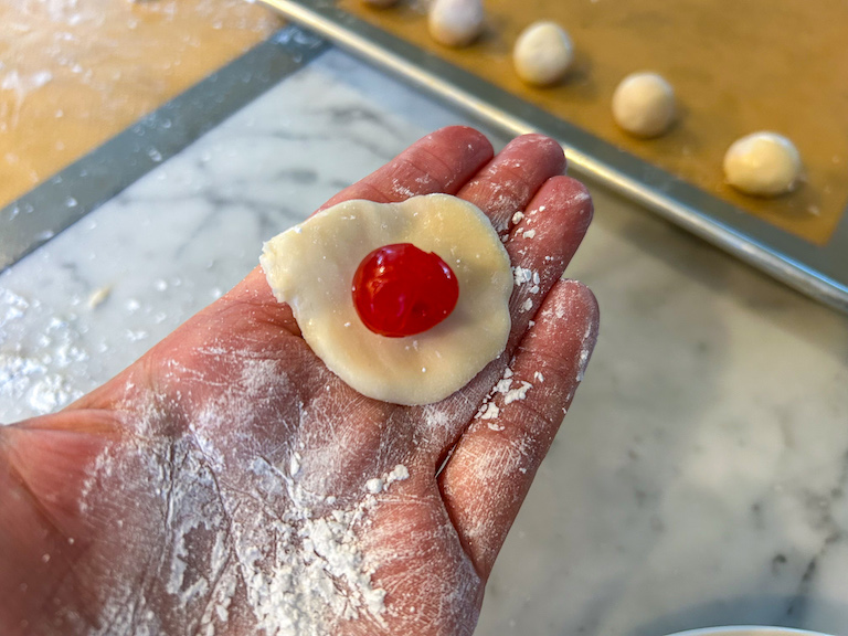 Hand holding a piece of fondant with a cherry in the middle