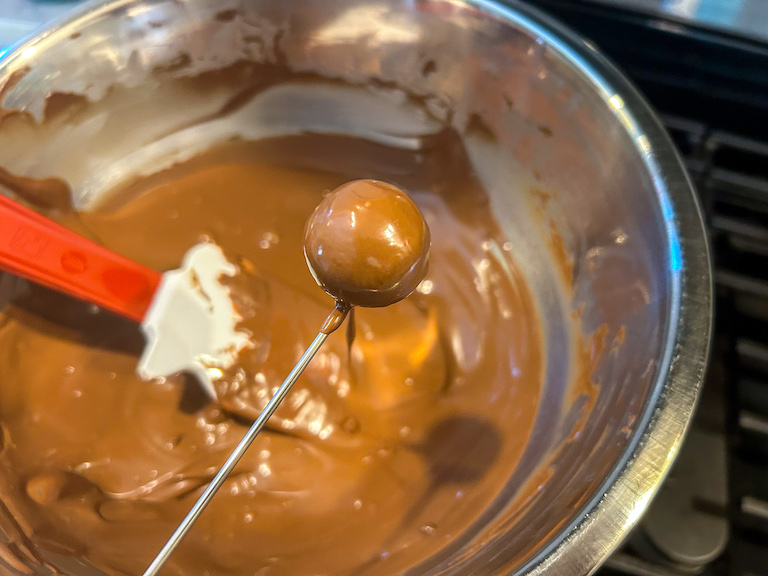 Enrobing fork dipping a fondant center in melted chocolate