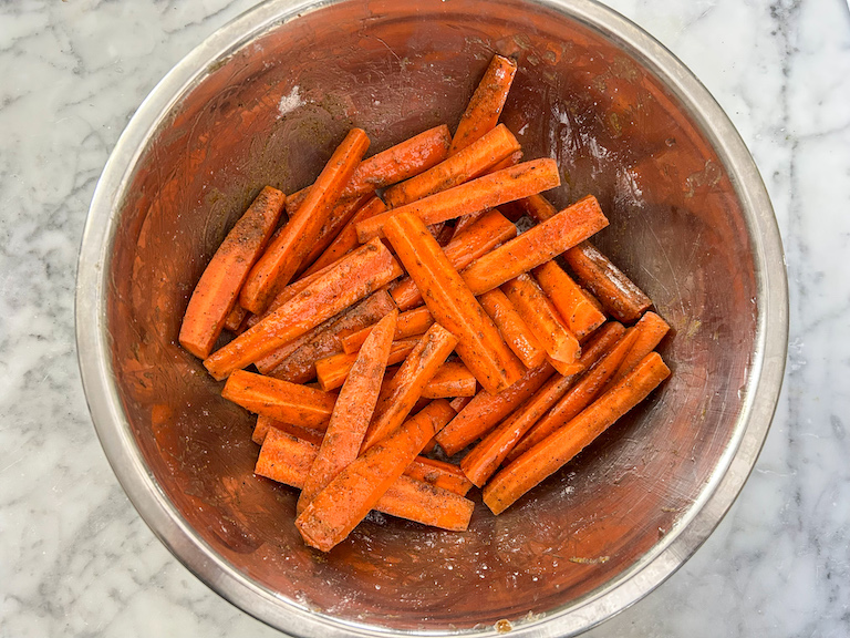 Bowl of carrot sticks with olive oil and spices