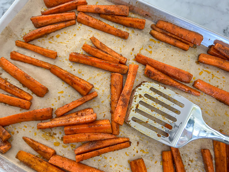 Metal spatula tossing carrot fries