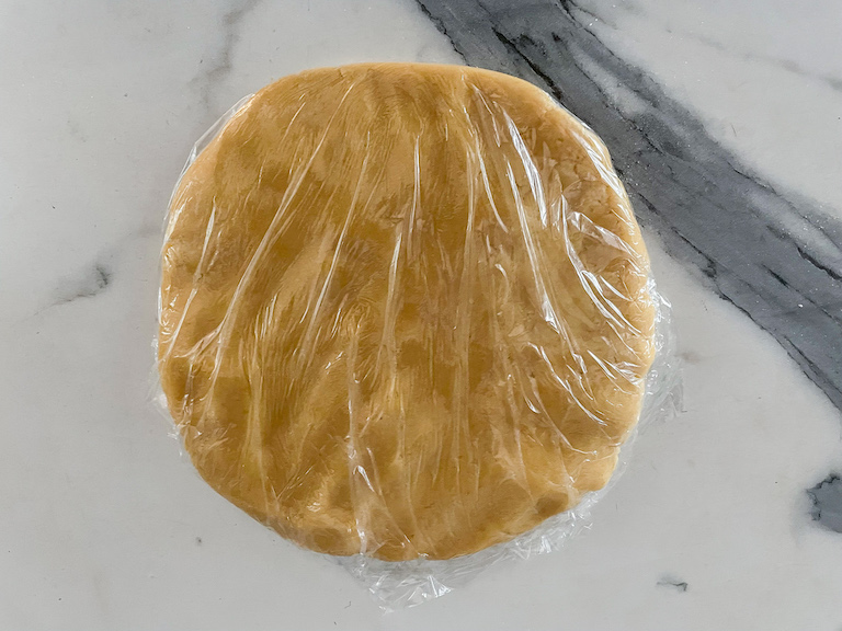 A disc of cookie dough wrapped in plastic wrap