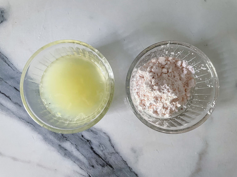 A dish of lemon juice and a dish of custard powder on a marble surface