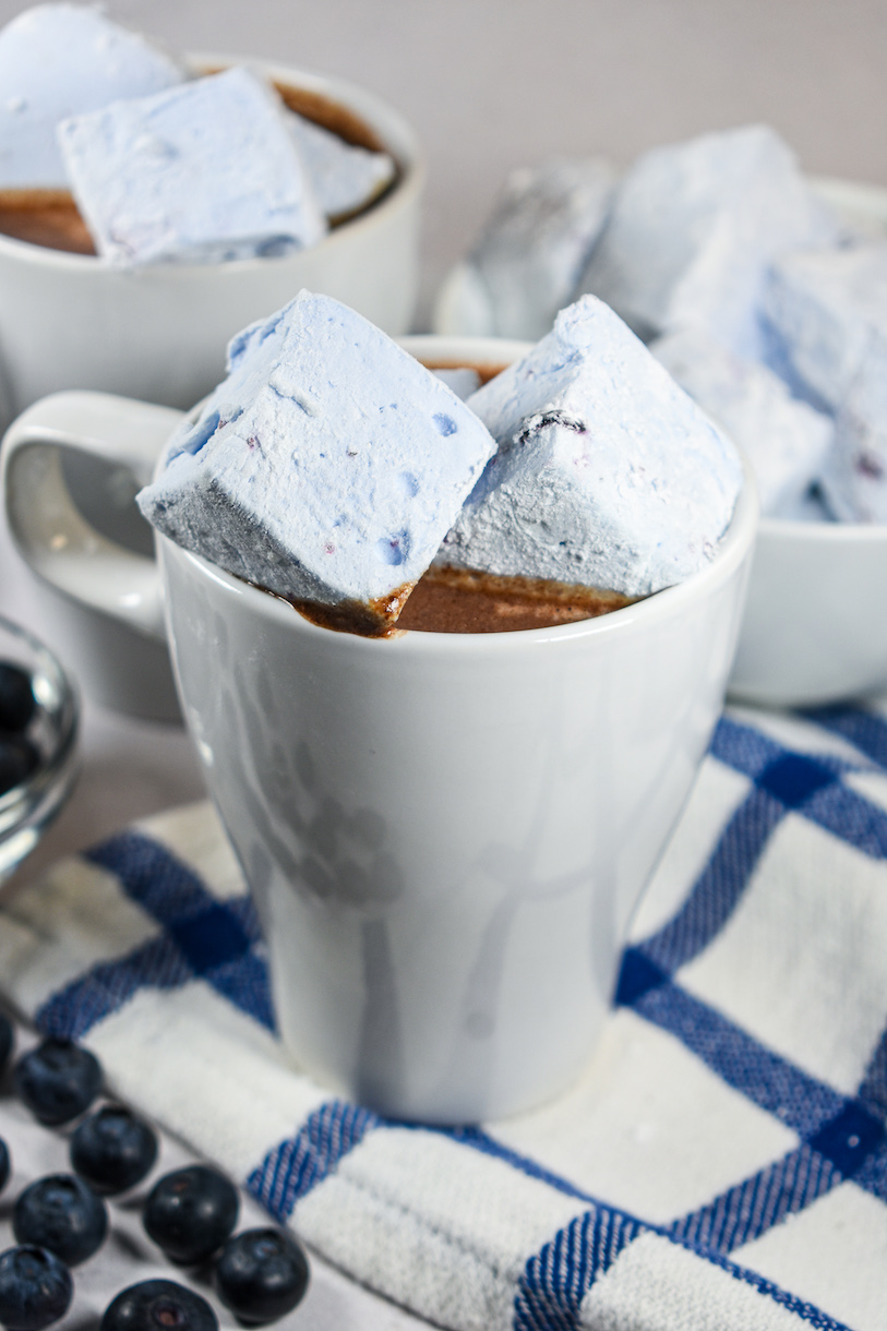 A mug of blueberry hot chocolate with blueberry marshmallows