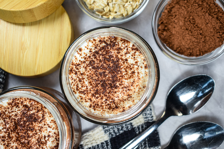 Looking down at jars of tiramisu overnight oats on a white surface