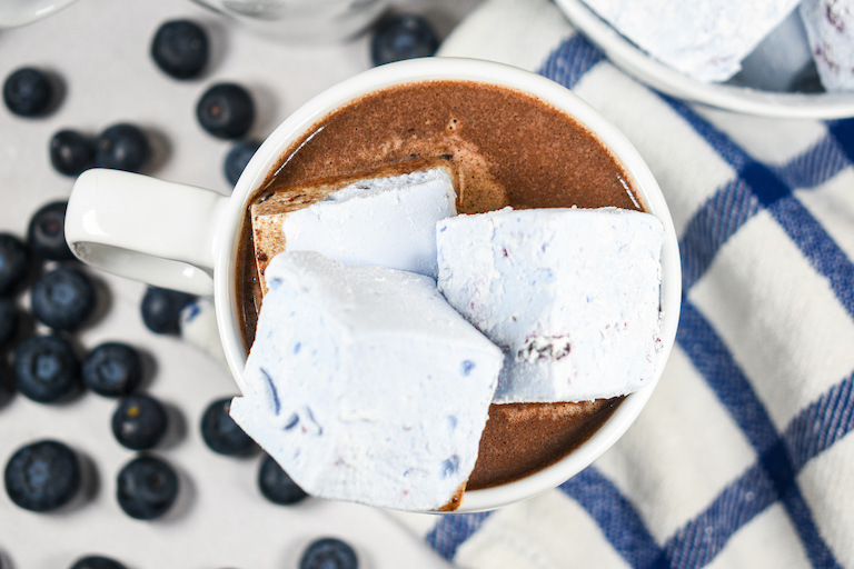 A mug of blueberry hot chocolate with blueberry marshmallows