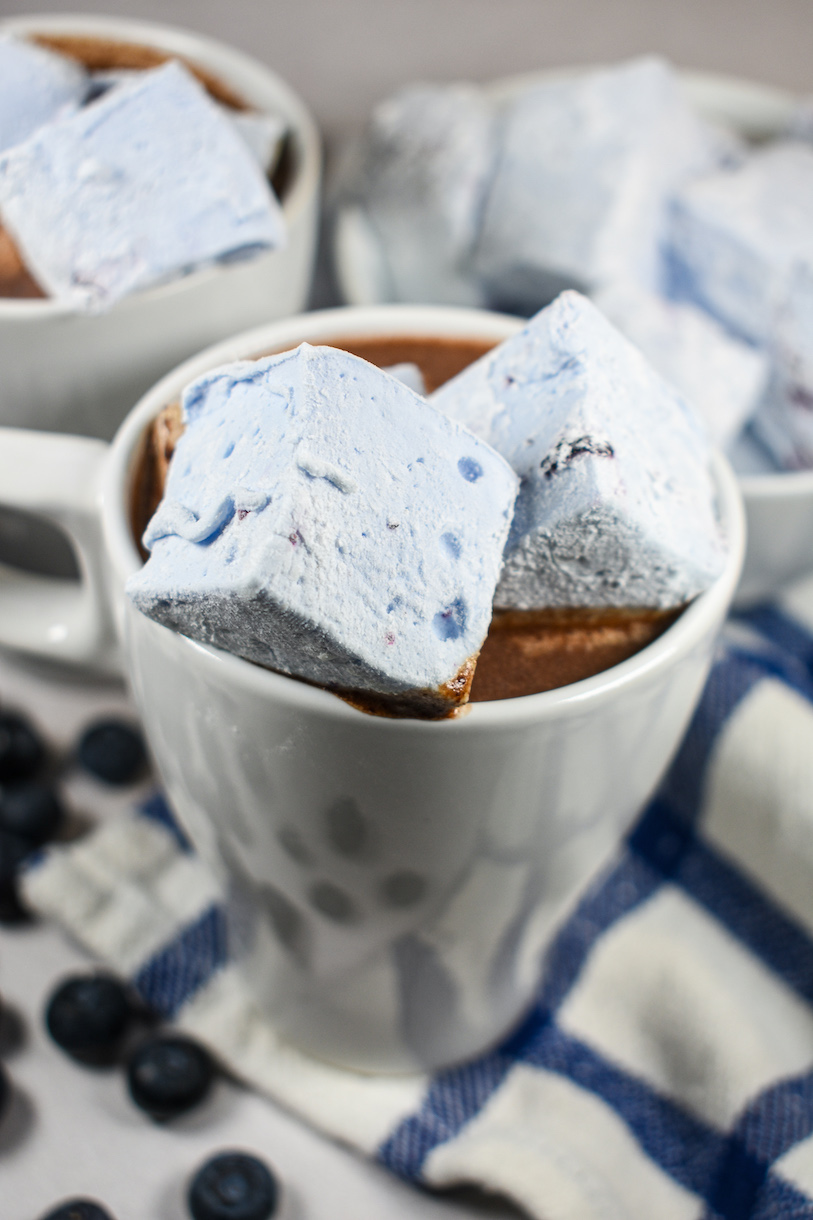 A mug of blueberry hot chocolate with blueberry marshmallows