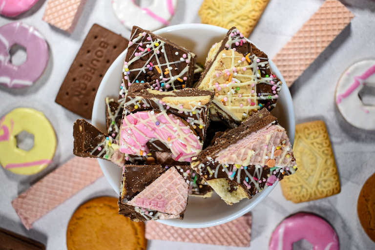 A bowl of chocolate bark surrounded by an assortment of British biscuits