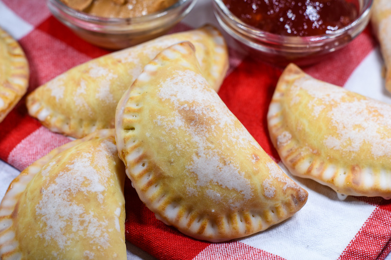 Peanut butter and jelly hand pies arranged on a red and white plaid towel