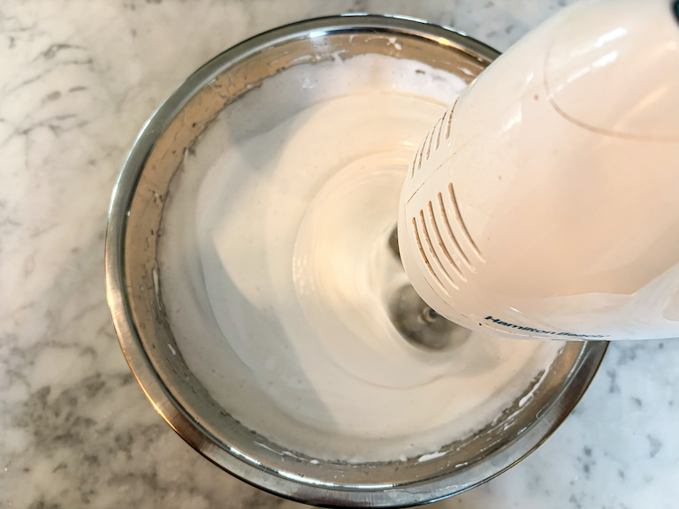 Mixing homemade marshmallow fluff with a hand mixer