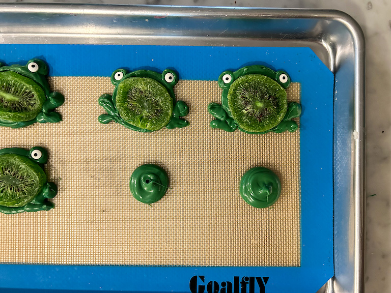 Piping chocolate frogs on a silicone mat
