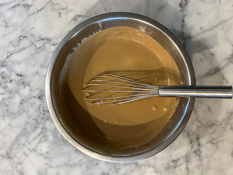 Cold brew ice cream base in a bowl with a metal whisk