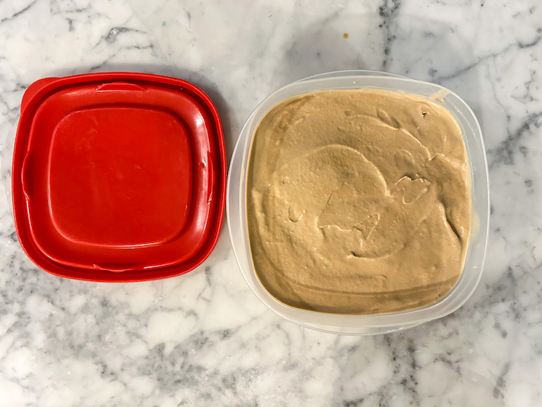 Cold brew ice cream in a plastic container with a red lid