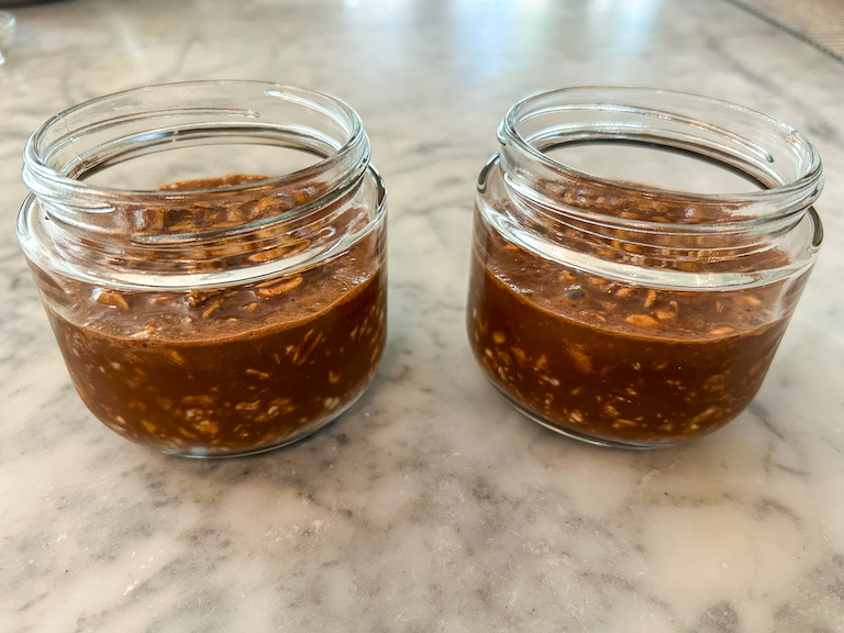 Two jars of overnight oats on a marble surface