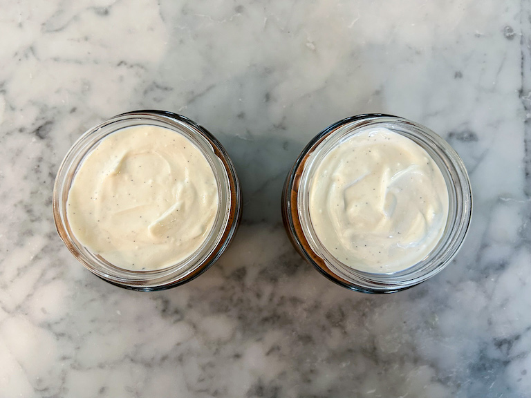Looking down at two jars of overnight oats on a marble surface