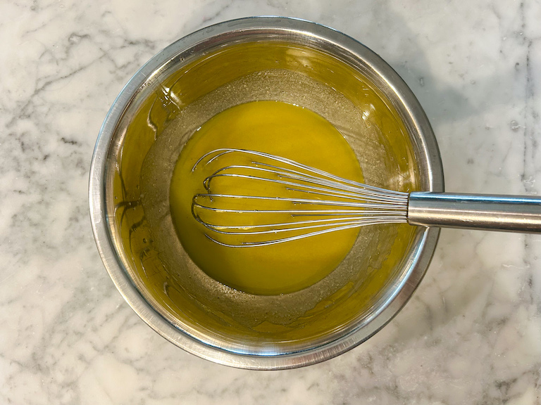 Whisking olive oil dressing in a metal bowl