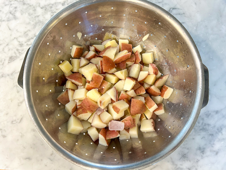 Cooked red potatoes in a metal colander