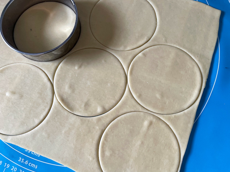 Round metal cutter cutting shortcrust pastry into discs