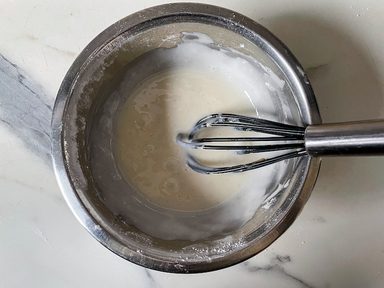 vanilla bean glaze in a bowl with a whisk