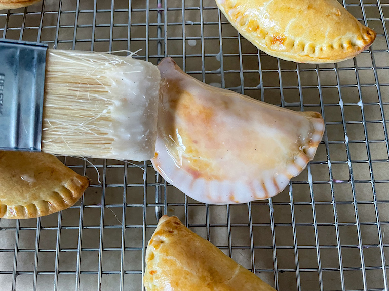 Brushing vanilla bean glaze over pb&j hand pies