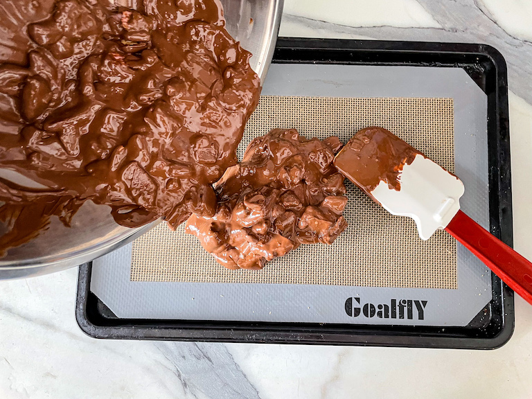 Spreading chocolate bark on a silicone mat with a rubber spatula