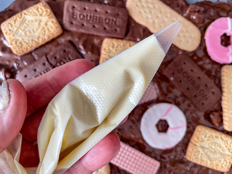 Hand holding a piping bag filled with melted white chocolate