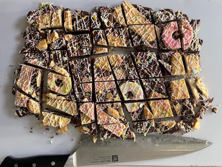 Chopped chocolate bark on a chopping board with a knife