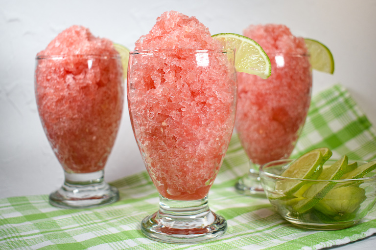 Glasses of watermelon granita garnished with slices of lime