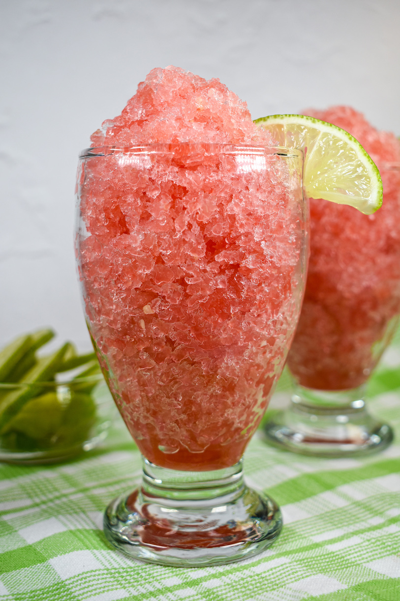 Two glasses of watermelon granita positioned on a green plaid towel