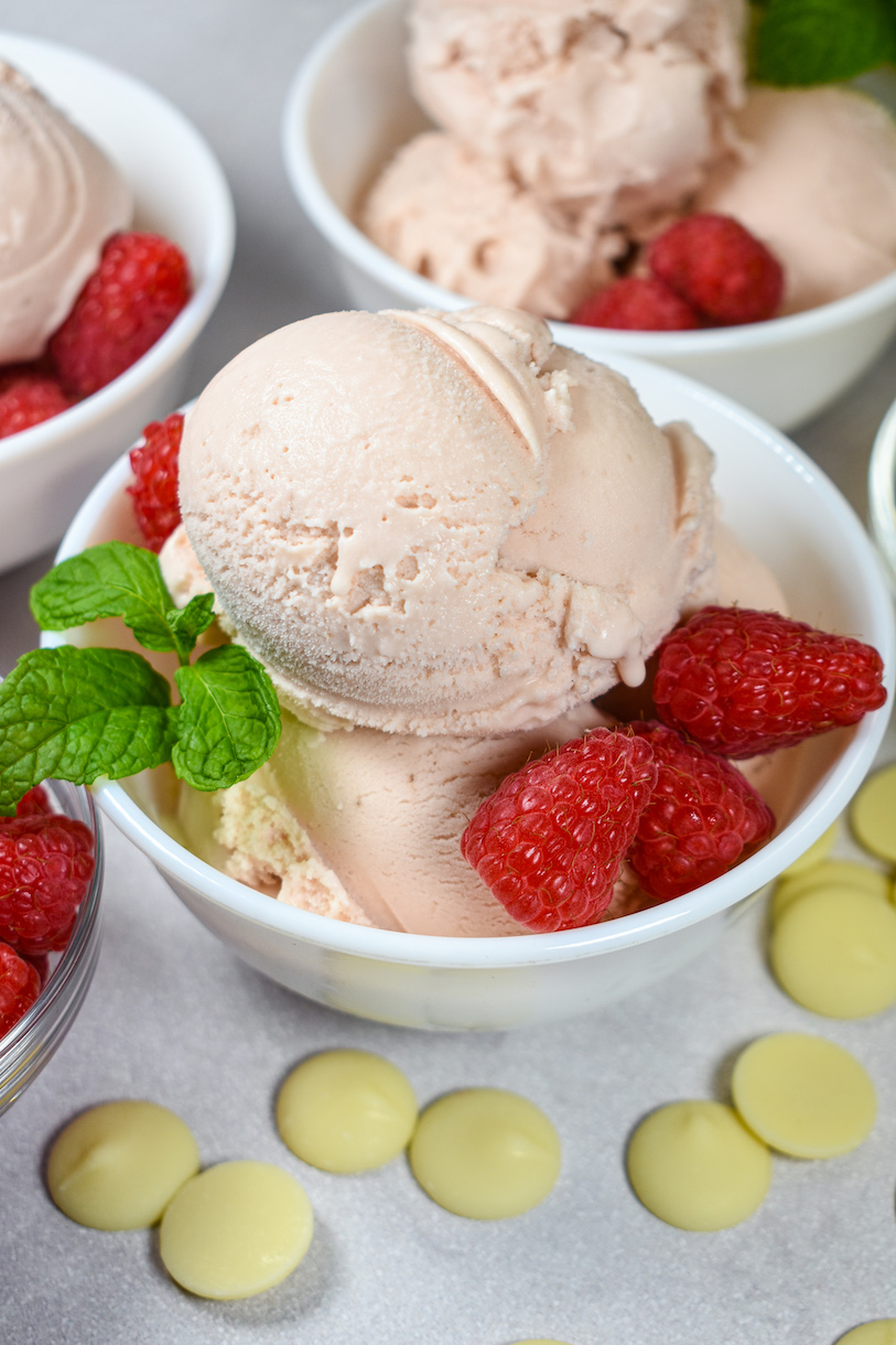 Bowls of raspberry white chocolate ice cream garnished with mint leaves and fresh raspberries