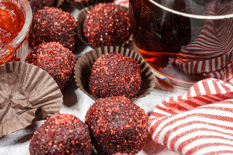 Cherry cola truffles on a white surface with a striped towel and a glass of soda