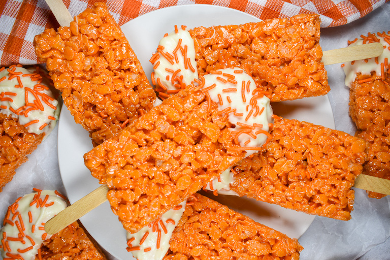 A pile of orange cereal treat popsicles arranged on a small white plate
