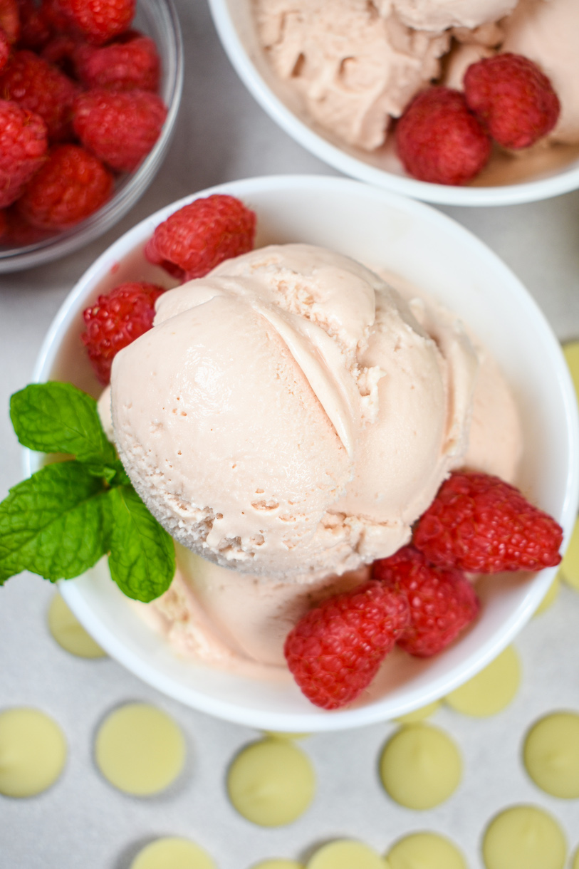 a dish of raspberry ice cream with raspberries and fresh mint leaves