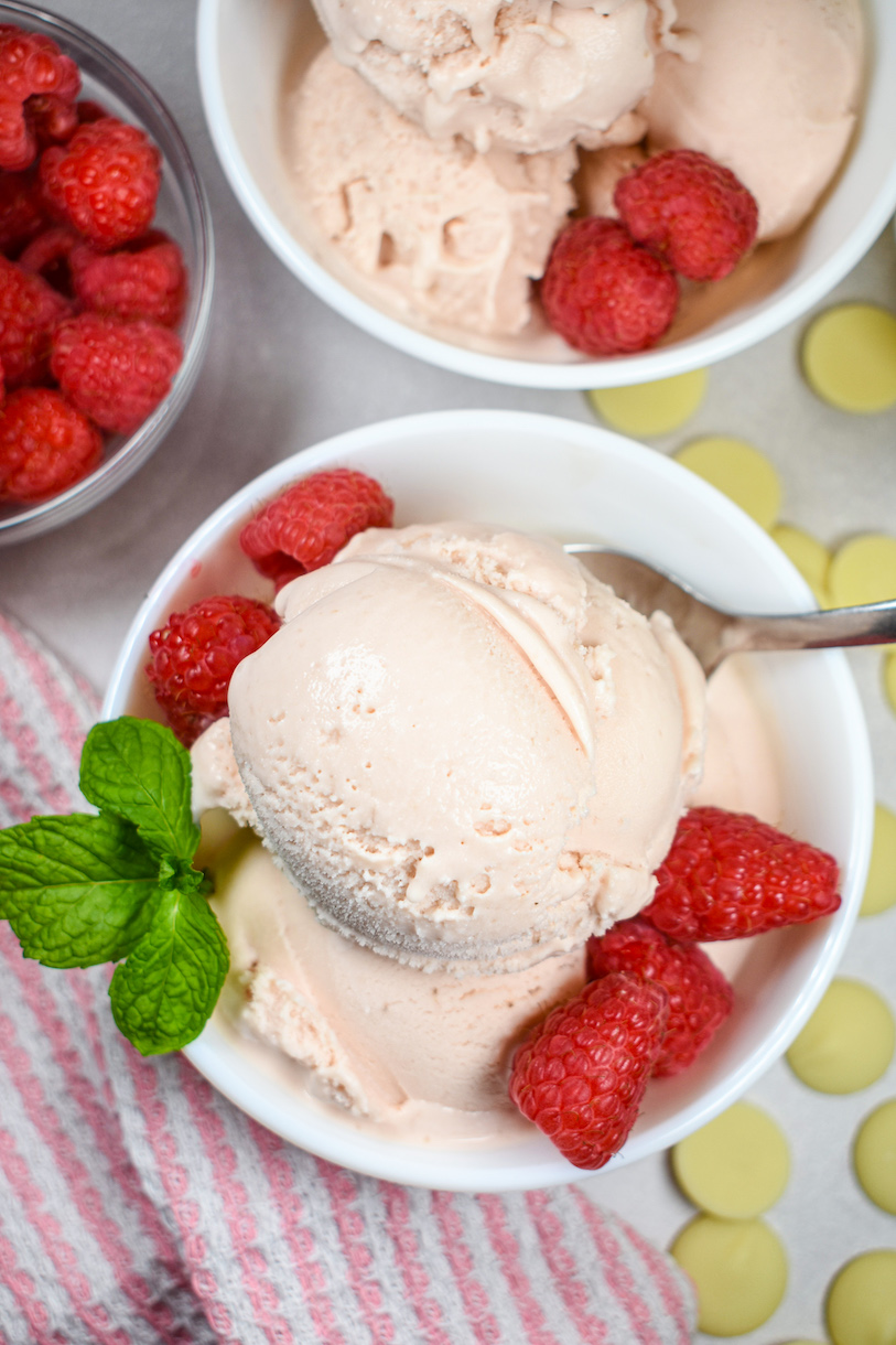 Looking down at dishes of white chocolate raspberry ice cream on a pink pattered tea towel