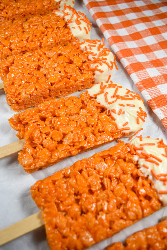 A row of orange krispie treat pops
