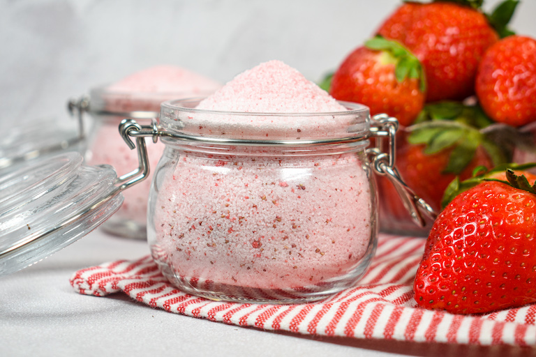  A jar of homemade strawberry sugar and a dish of fresh strawberries