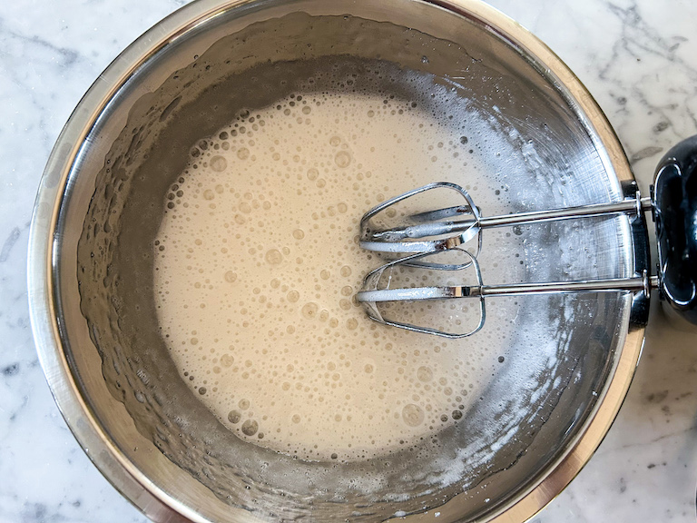 Mixing marshmallow sugar syrup in a bowl with a hand mixer