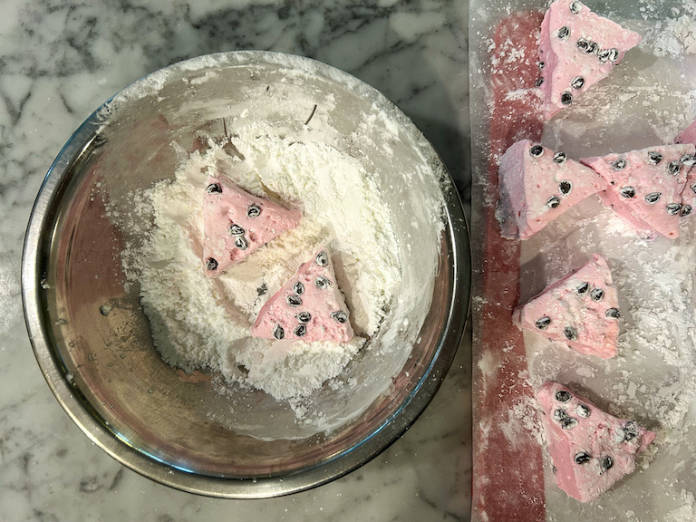 Wedges of watermelon marshmallow in a bowl of powdered sugar and cornstarch