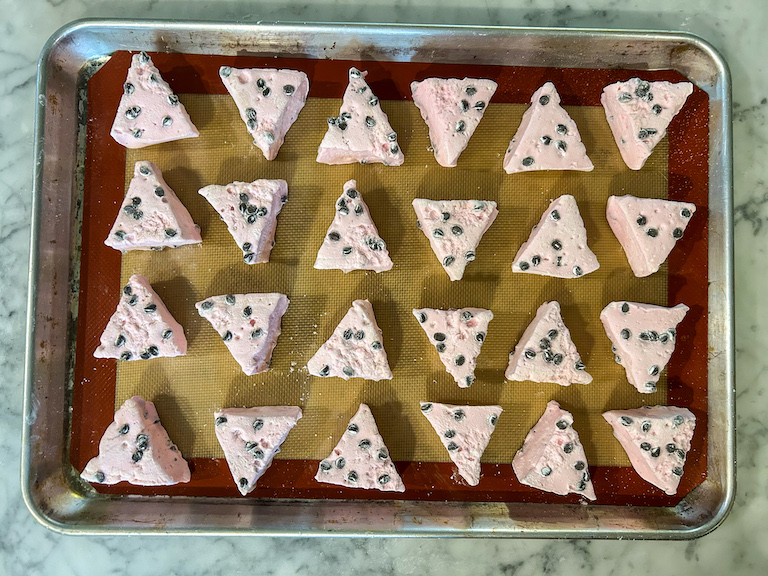 Pink, triangle-shaped marshmallows arranged on a metal tray