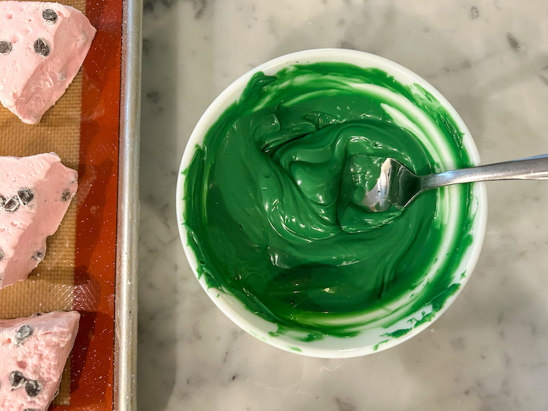 A small bowl of melted green chocolate with a spoon