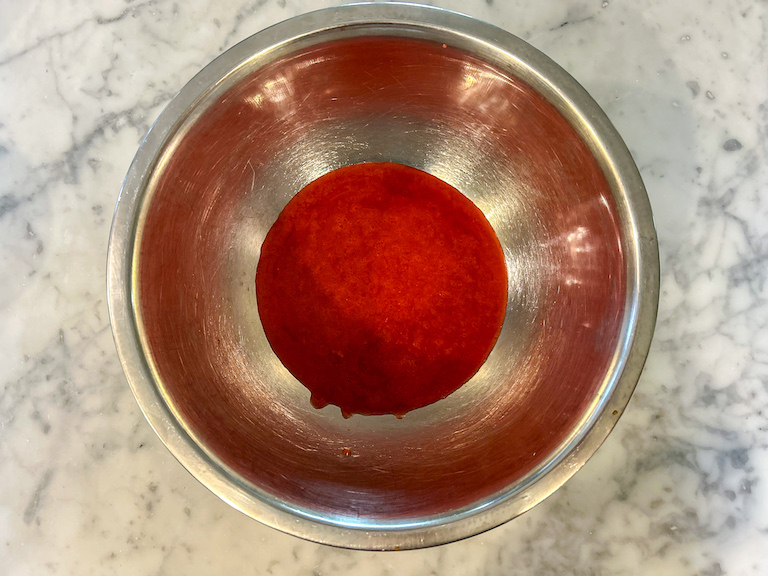 A metal bowl of raspberry puree