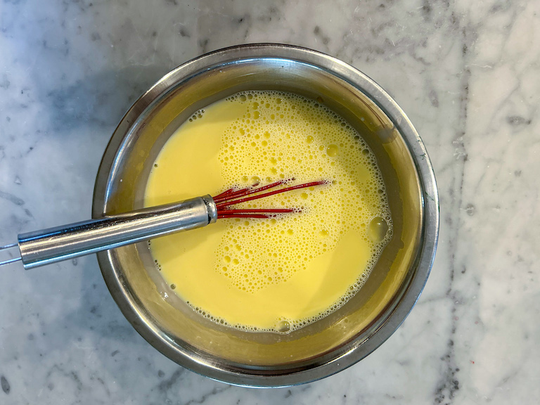 Tempered ice cream base in a metal bowl with a whisk