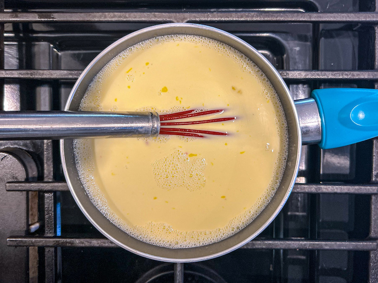 Ice cream base in a saucepan on the stovetop with a whisk