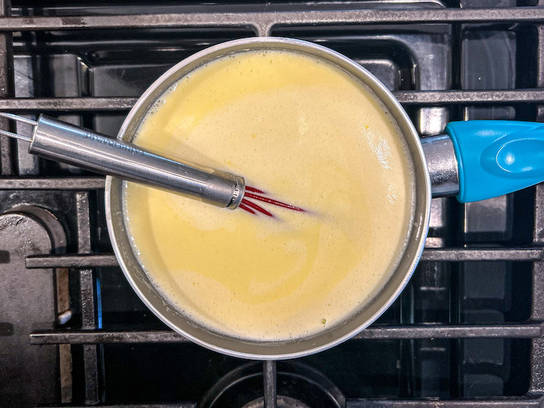 Ice cream base in a saucepan on the stovetop with a whisk