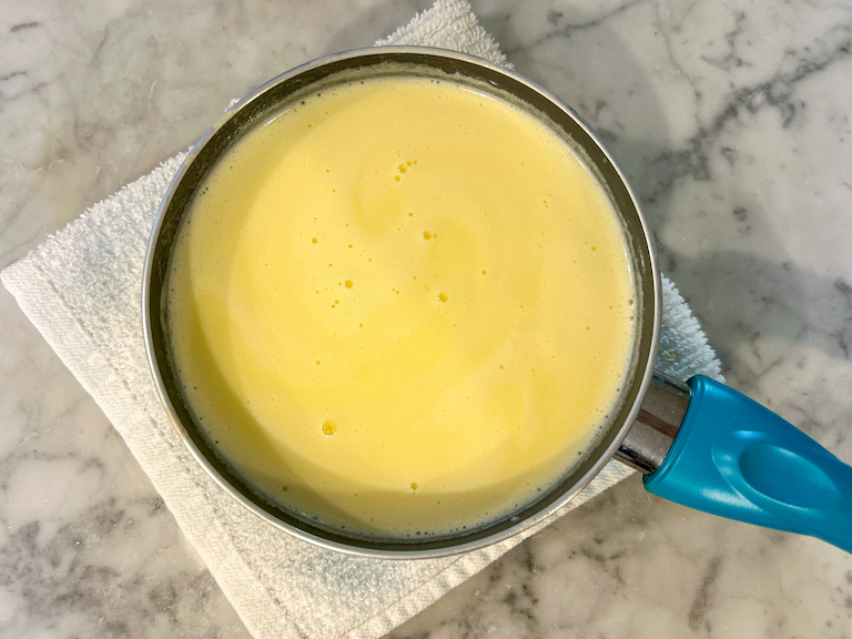 White chocolate ice cream base in a small saucepan on a marble surface