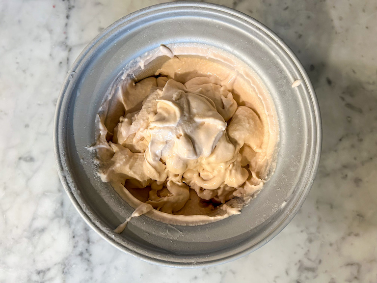 Churned ice cream in ice cream maker bowl on a marble surface